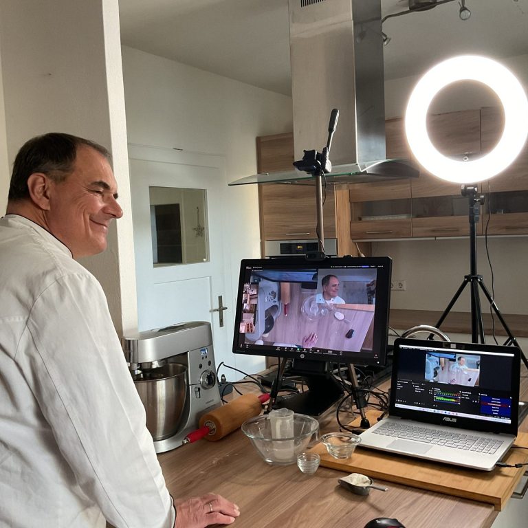 Ein Bäcker steht an einer Arbeitsplatte mit Laptop und Computer